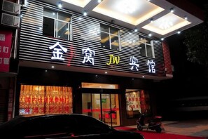 Un edificio con un letrero que dice '金居 JW酒店' y un coche estacionado en la entrada.