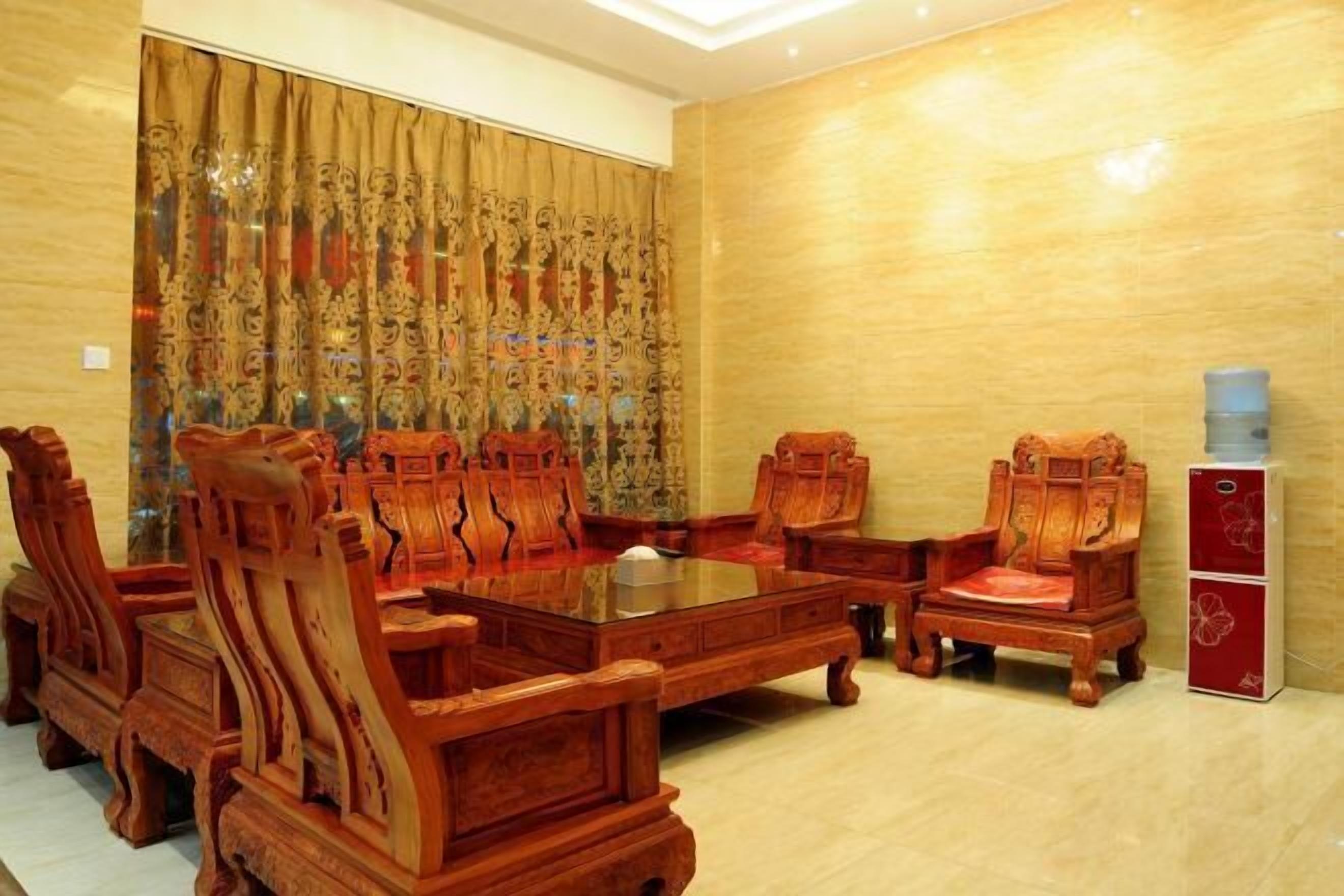 Ein Konferenzraum mit einem großen Holztisch, passenden Stühlen, einem roten Sofa und einem Wasserspender.