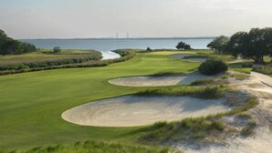 Un campo da golf con bunker di sabbia, specchi d'acqua e un ponte sullo sfondo.