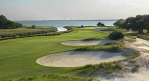 A golf course with sand bunkers, a water body, and a bridge in the background. - 2-bedroom condo in delightful Fort Pierce with WiFi, AC, fitness room (Fort Pierce)