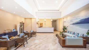 Un vestíbulo amplio con una mesa de recepción, muebles de mimbre y un mural grande en la pared.