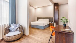 A hotel room with a bed, a wicker chair, a desk, and a potted plant. - Manfu Hotel (Beibei Southwest University Zhuangyuanbei Subway Station Branch) (Chongqing)