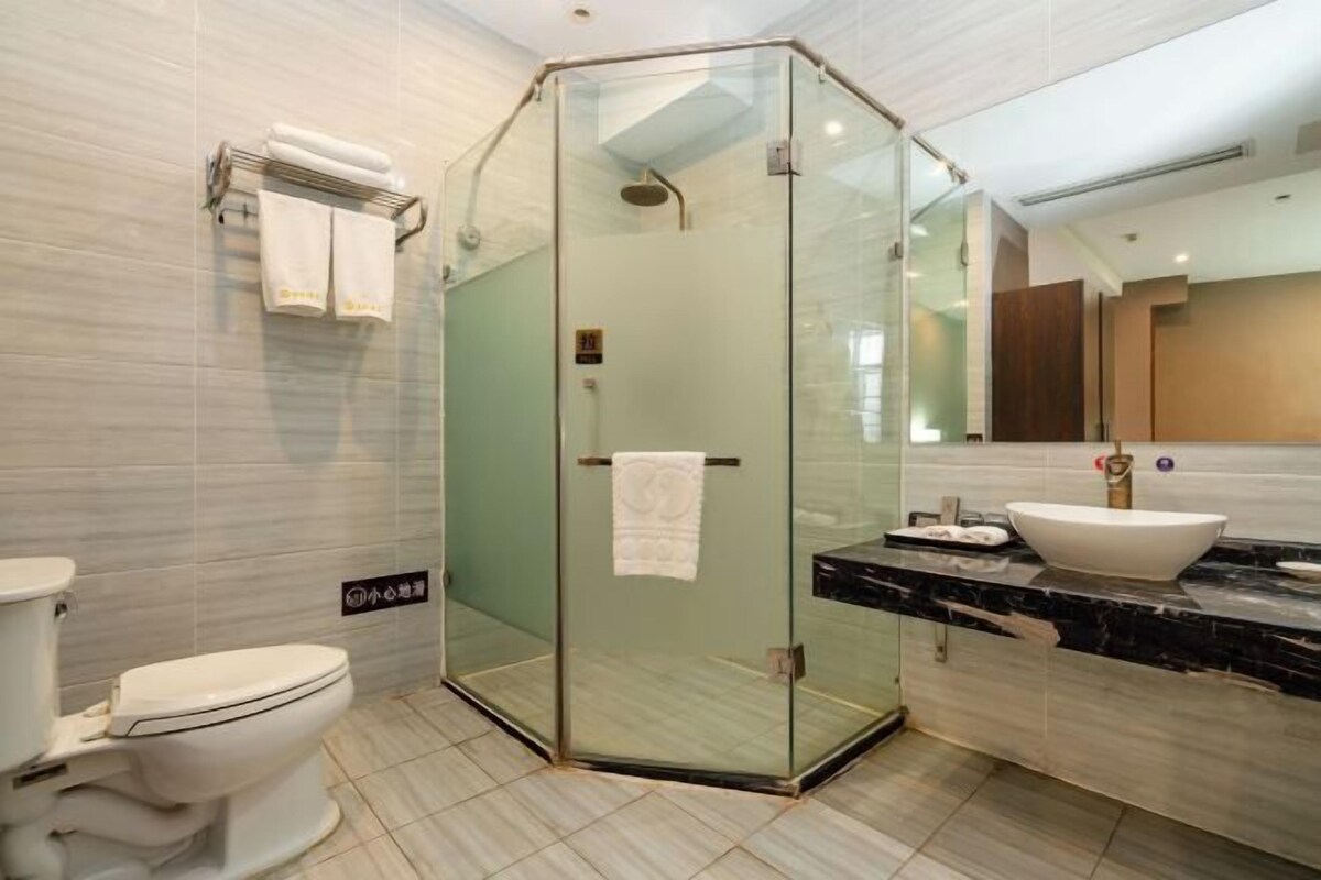 A modern bathroom with a glass-enclosed shower, a white toilet, and a marble sink.