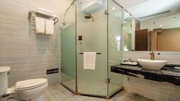 A modern bathroom with a glass-enclosed shower, a white toilet, and a marble sink.