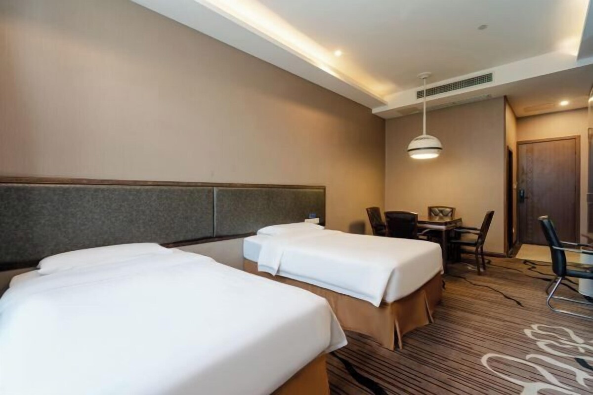 A hotel room with two beds, a desk, and a chair.