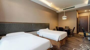 A hotel room with two beds, a desk, and a chair.