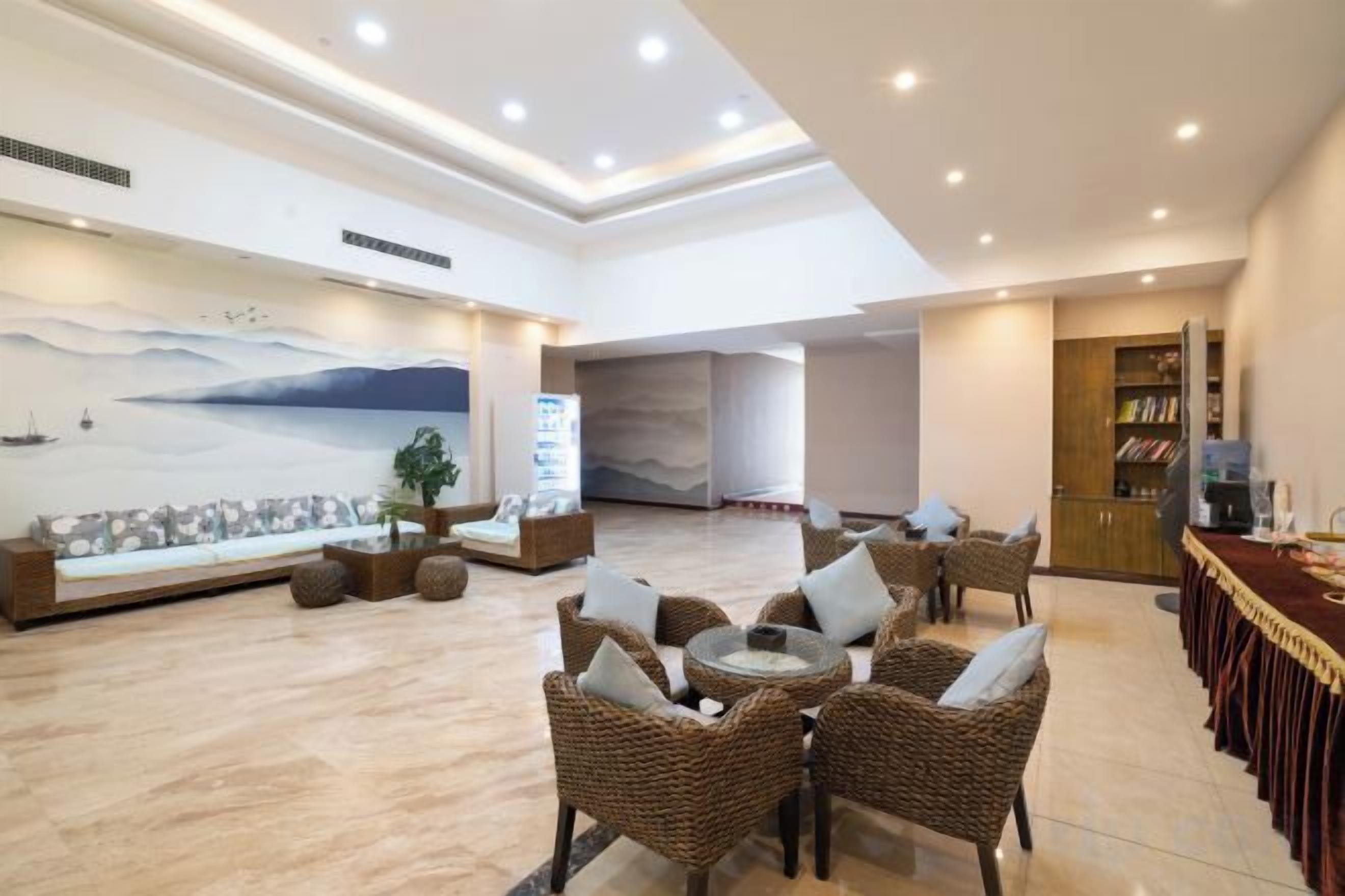 A spacious lobby with a seating area, a large wall mural, and a reception desk.