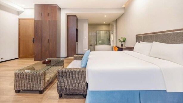 A modern hotel room with a large bed, a wardrobe, a seating area, and a view of the bathroom. - Manfu Hotel (Beibei Southwest University Zhuangyuanbei Subway Station Branch) (Chongqing)