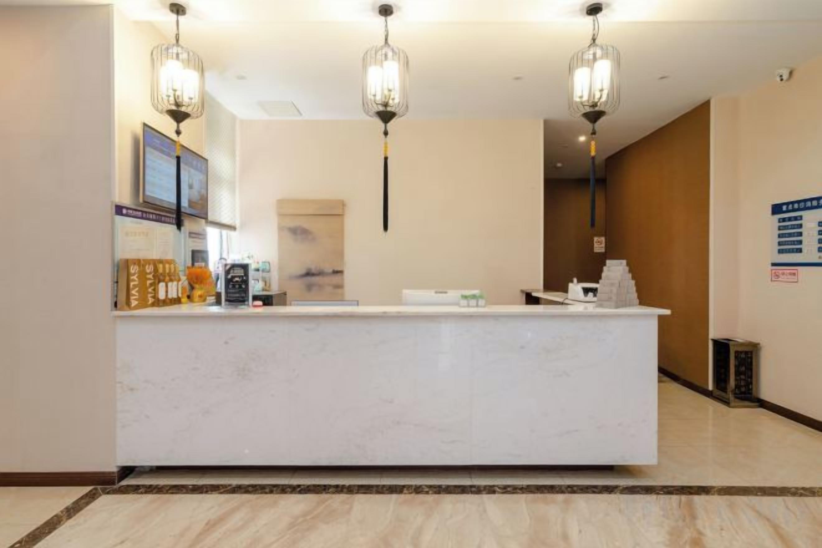 A reception desk with a marble top, two hanging light fixtures, and a framed picture on the wall.