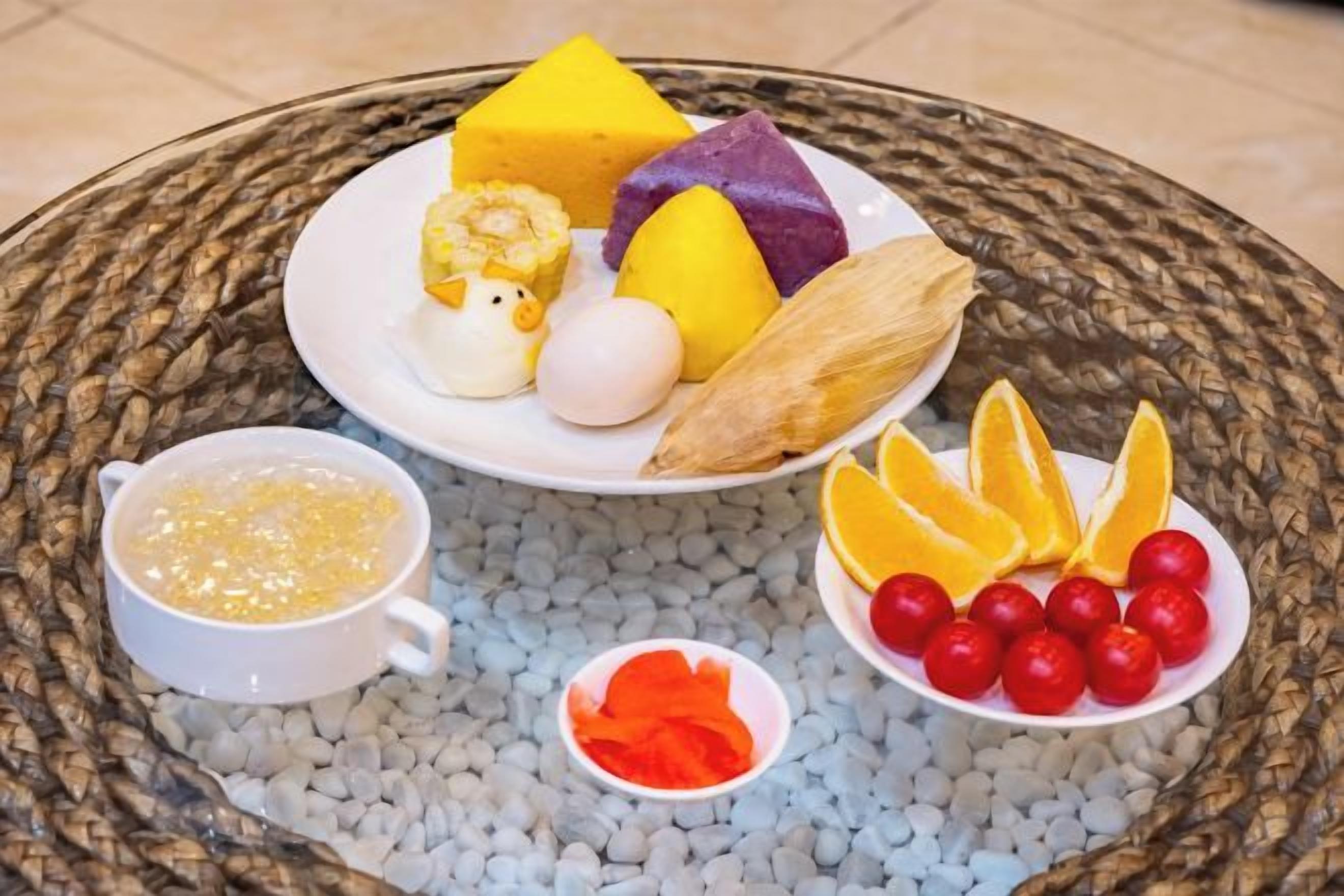 Un plato con diferentes alimentos, incluyendo un cubo amarillo, un cubo morado, una mazorca de maíz y un huevo entero.