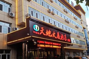 Un edificio de varios pisos con un letrero llamativo que muestra un logotipo y caracteres chinos.