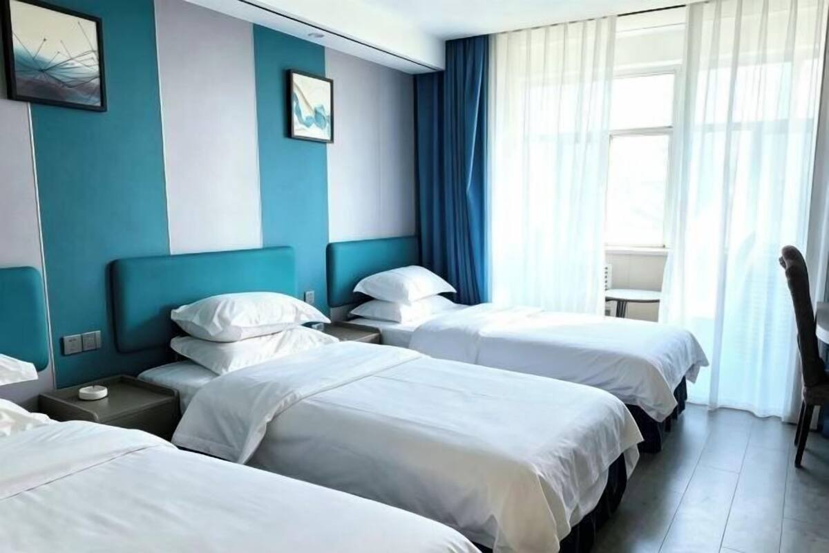 A hotel room with two beds, a desk, and a chair.
