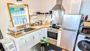 A modern kitchen with a dining area, featuring a stove, oven, refrigerator, and a sink.