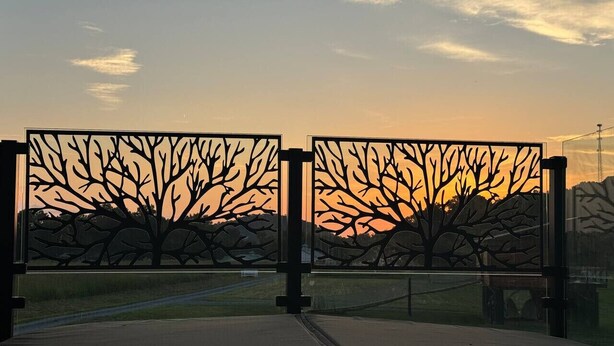 A metal gate with tree designs, a concrete pathway, and a clear sky. - Morticia & Gomez Treehouse. Hot tub. Riverfront. (Sevierville)