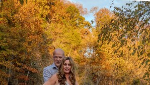 A couple standing in a river with autumn foliage in the background. - Morticia & Gomez Treehouse. Hot tub. Riverfront. (Sevierville)