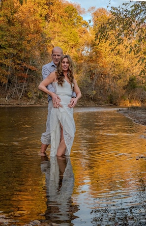 A couple standing in a river surrounded by autumn foliage. - Morticia & Gomez Treehouse. Hot tub. Riverfront. (Sevierville)