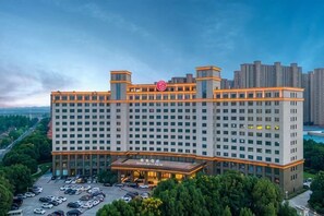 A large hotel with multiple floors, a prominent entrance, and a parking lot. - Rich Global Hotel (Li County)