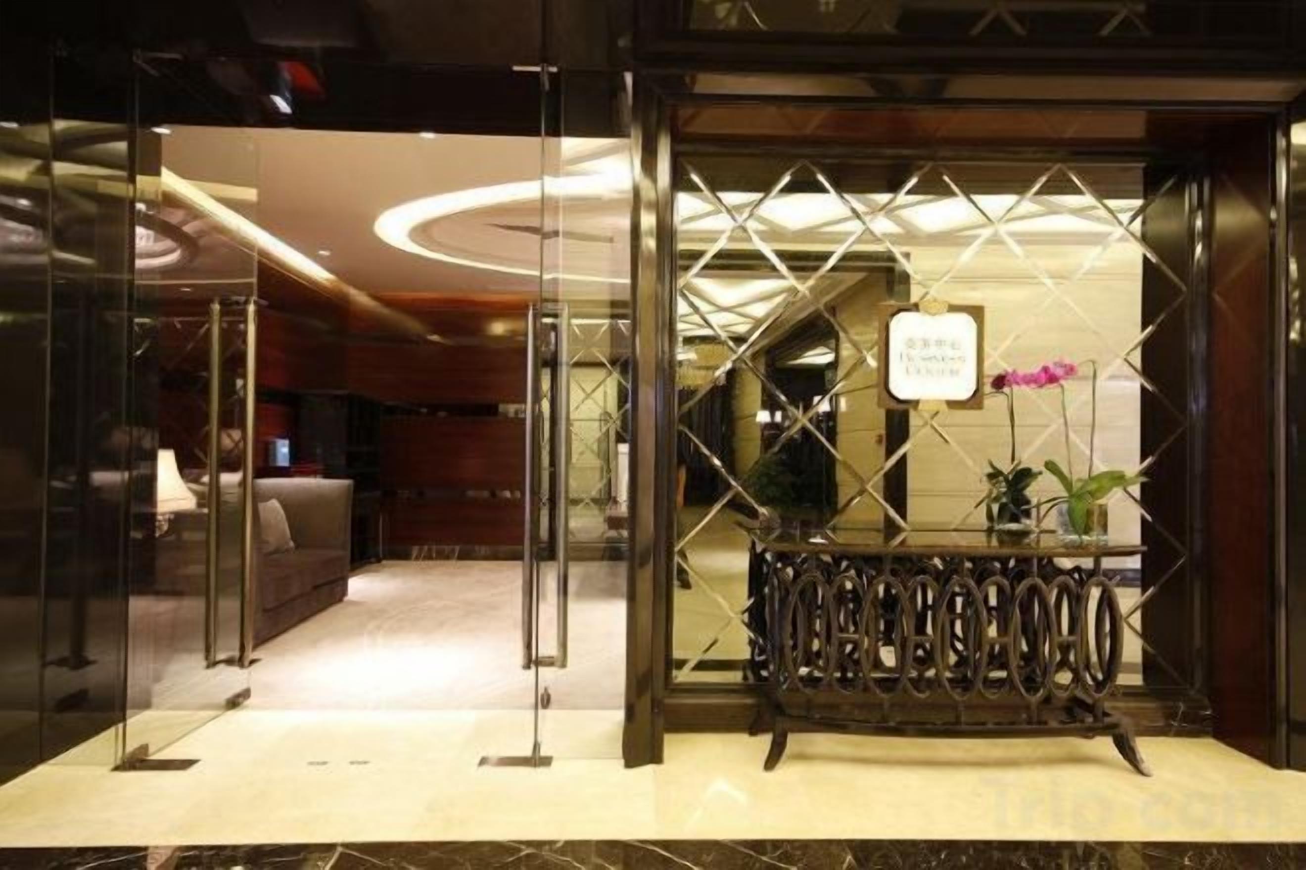 A hotel entrance with a reception desk, glass doors, and a modern interior design.