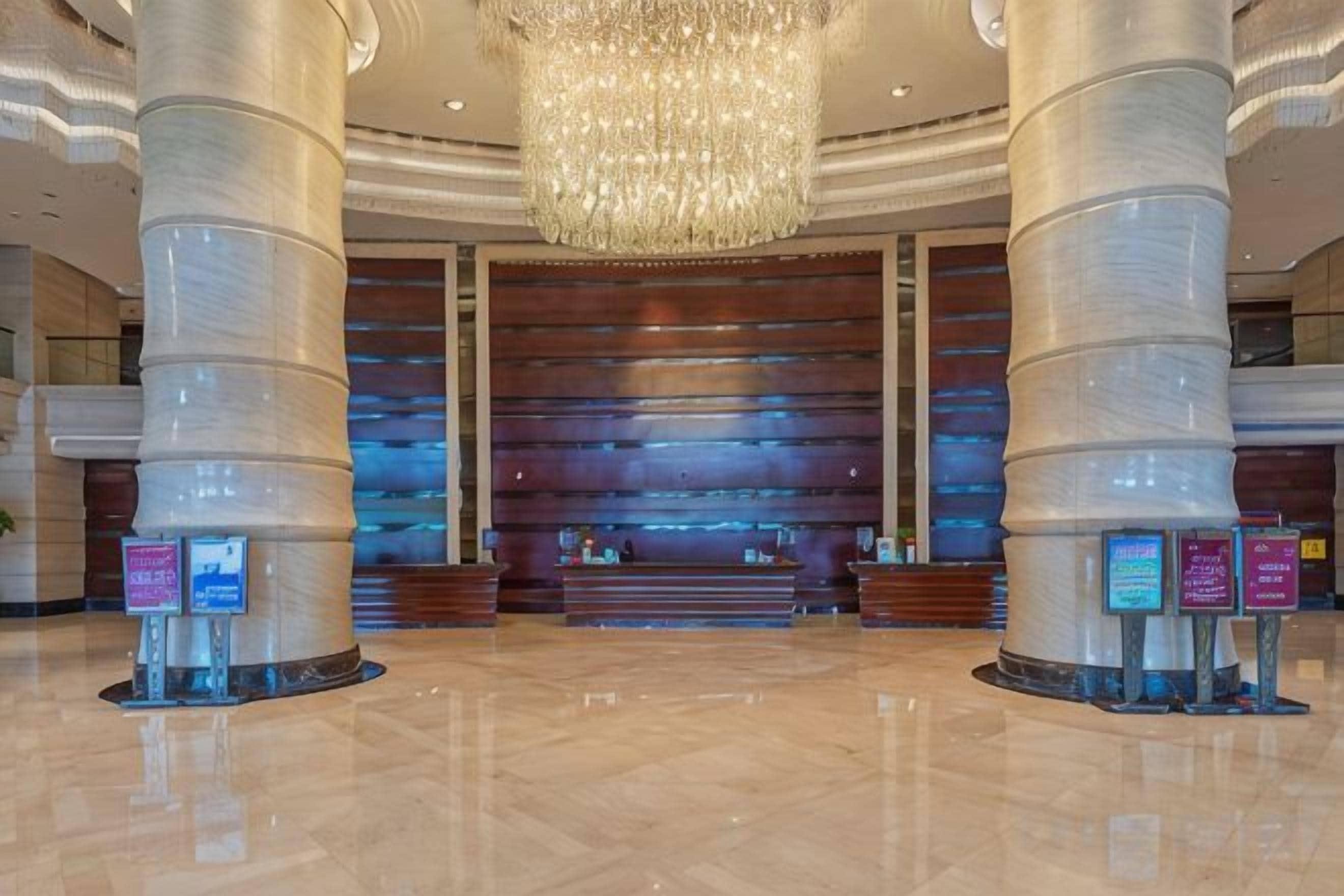 A spacious lobby with a large chandelier, polished floors, and a reception desk.