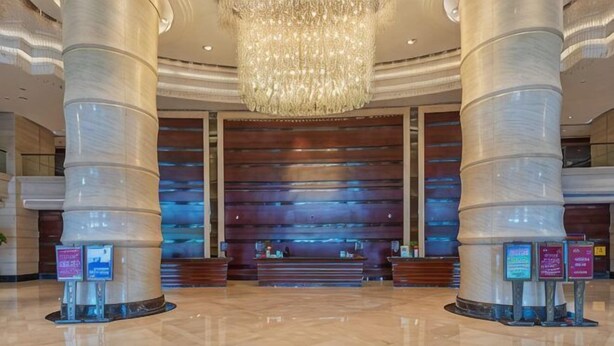 A spacious lobby with large columns, a chandelier, and a reception desk. - Rich Global Hotel (Li County)