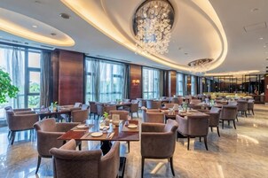 A modern restaurant with round tables, chairs, and a large chandelier.