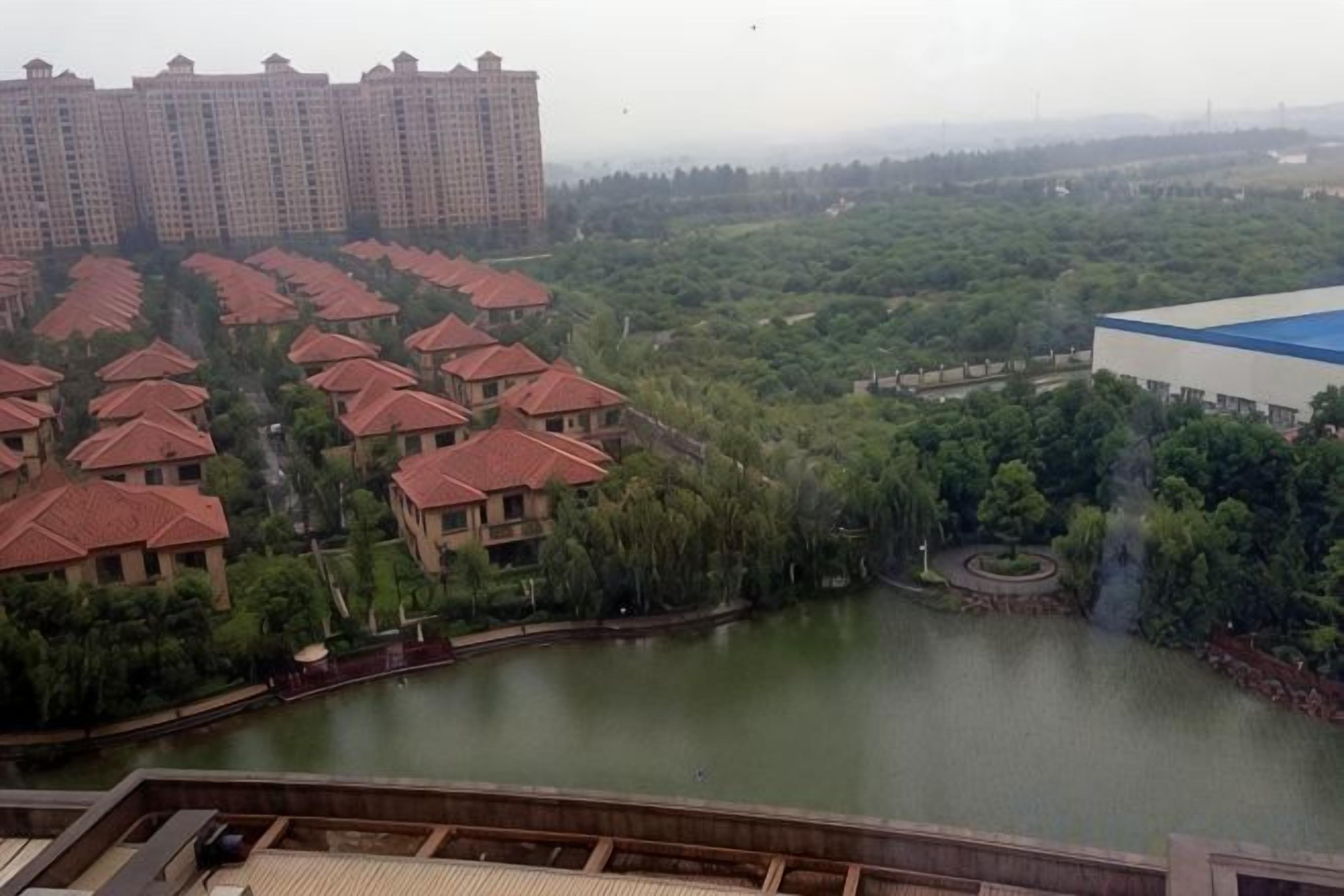 A residential area with multiple buildings, a body of water, and a large structure with a blue roof.