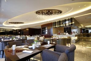 A modern hotel lobby with a central bar area, seating arrangements, and a chandelier. - Rich Global Hotel (Li County)