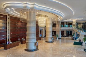 A spacious lobby with a curved ceiling, large columns, and a staircase. - Rich Global Hotel (Li County)