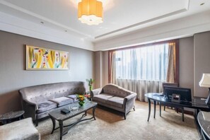 A modern hotel room with a sofa, armchair, coffee table, and a desk with a computer. - Rich Global Hotel (Li County)