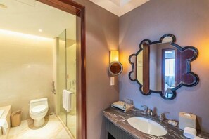 A modern bathroom with a glass shower enclosure, a marble sink, and a large mirror with a decorative frame. - Rich Global Hotel (Li County)