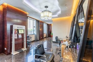 A hotel lobby with a reception desk, a waiting area with chairs, and a large window.
