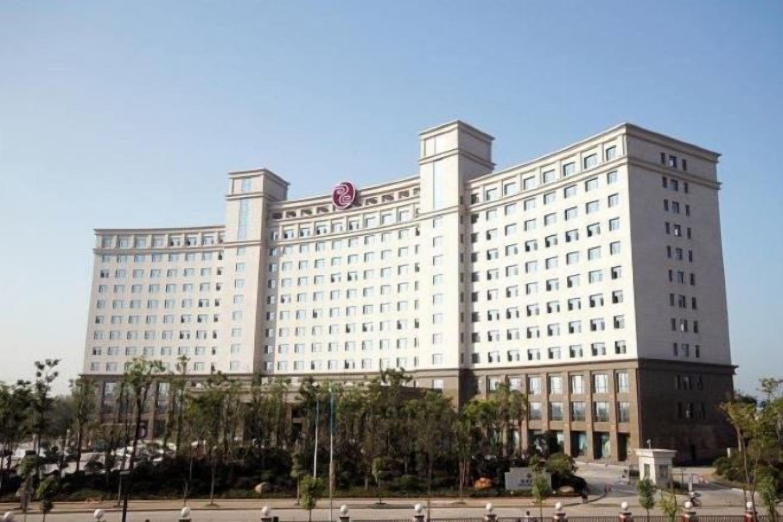 Un hotel de varios pisos con una fachada simétrica, numerosas ventanas y una entrada central.