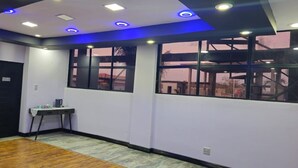 A room with a wooden floor, a desk with a chair, a window with a view, and recessed ceiling lighting. - Adelina Hotel (Rustenburg)