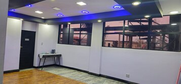 Habitación con suelo de madera, un escritorio con silla, ventana con vistas e iluminación empotrada en el techo.