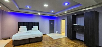 Una habitación de hotel moderna con una cama grande, suelo de madera oscura y vestidor.