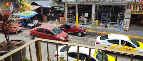 A street view with a yellow taxi, a red car, and a white car parked on the side.