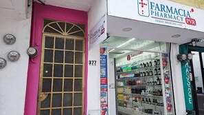 A pharmacy with a pink door and a signboard. - Casa Maruja Roomies House (Puerto Vallarta)