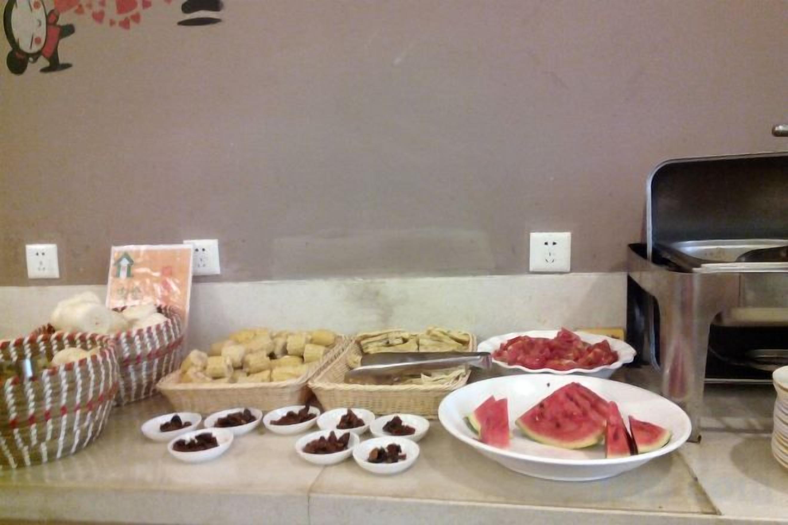 A buffet with various food items including fruits, pastries, and a watermelon slice.