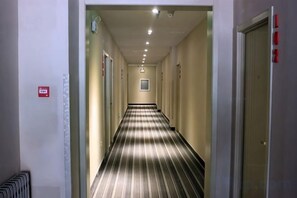 A hallway with a striped carpet, doors on both sides, and a fire alarm on the left wall. - Fanke Hotel (Jinan Railway Station South Square Branch ) (Jinan)