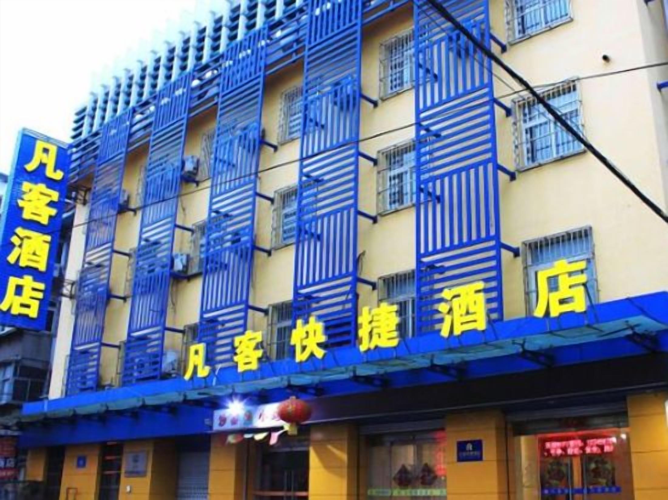 Fachada de hotel con persianas azules y señalización amarilla.