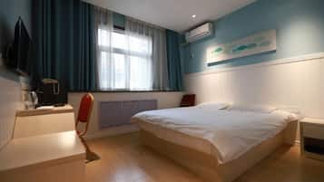 Habitación de hotel con cama, escritorio, silla, ventana con cortinas y un cuadro en la pared.