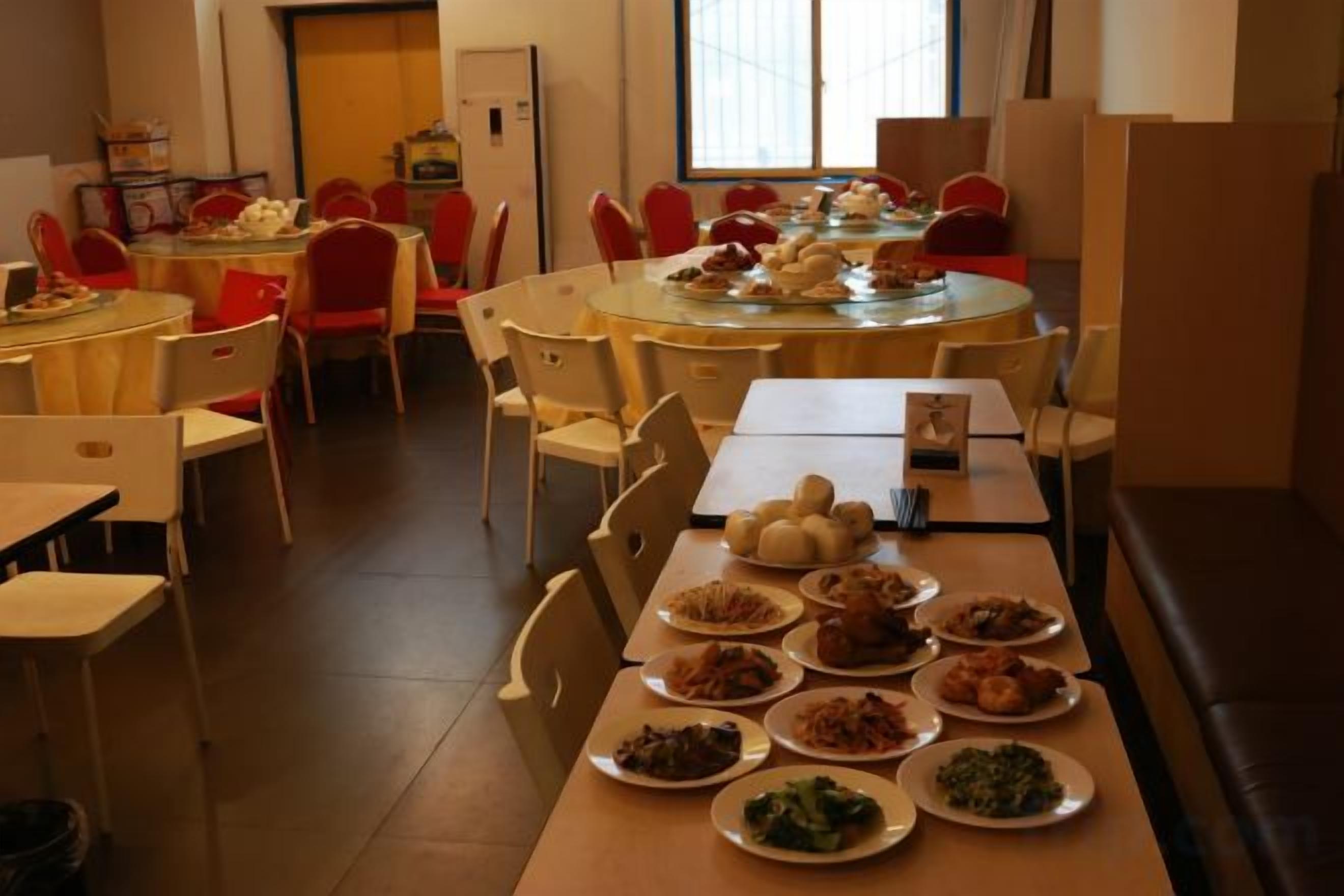 A dining area with multiple tables and chairs, some with plates of food.
