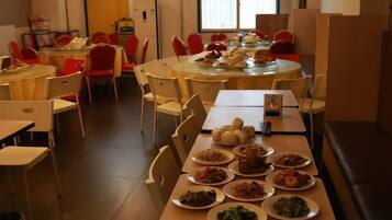 A dining area with multiple tables and chairs, some with plates of food.