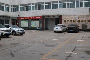 Un parking où plusieurs voitures sont garées devant un bâtiment orné d’une enseigne rouge.