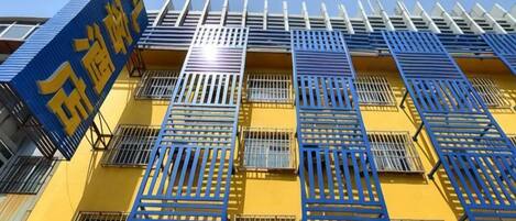 Een gebouw met een gele gevel en blauwe raamkozijnen, met een bord met Chinese karakters.