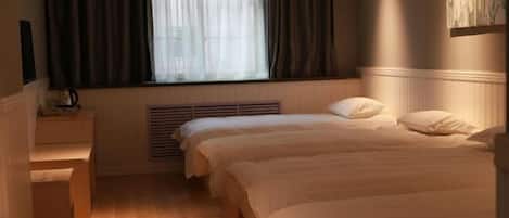 A hotel room with two beds, a window with curtains, a radiator, and a wall-mounted air conditioner.