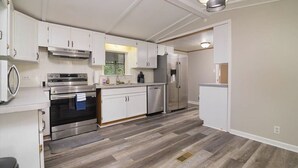 Una cucina moderna con mobili bianchi, elettrodomestici in acciaio inossidabile e pavimento in legno.