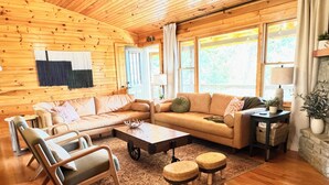 A cozy log cabin interior with a wooden floor, two sofas, a coffee table, and a rug. - Hot tub, theater room w/100" tv, views, firepit, 3 king beds, porch perfection! (Maggie Valley)