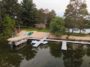 A lakeside dock with boats, a house, and surrounding trees.