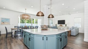 A spacious kitchen with a large island, pendant lighting, and a dining area with a view of the outdoors.
